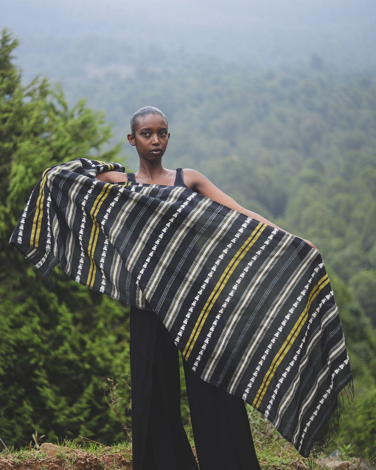 Person holding a striped fabric in a forest setting