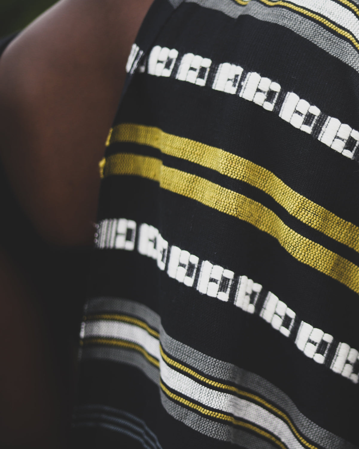 Close-up of a striped shirt with black, yellow, and white patterns.