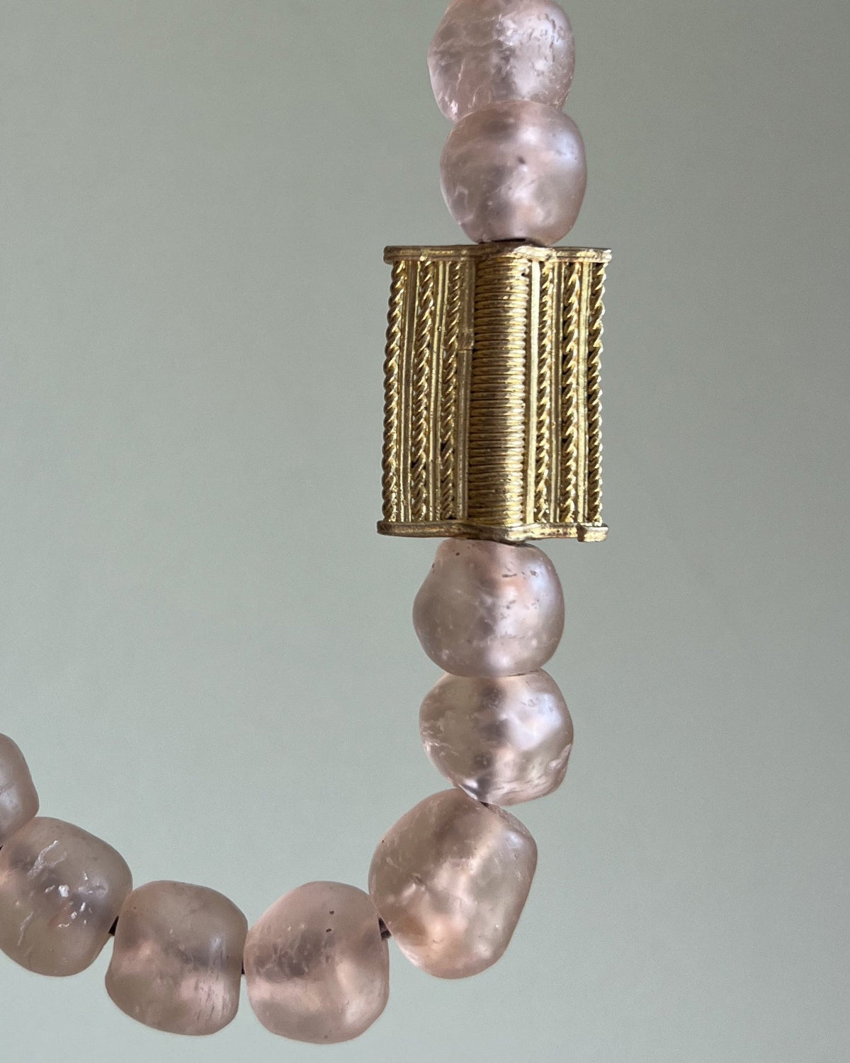 A necklace with a mix of pink and clear glass beads, featuring a gold-colored clasp.