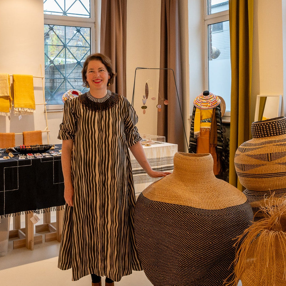 Woman standing in a store with various items on display, including a large vase.