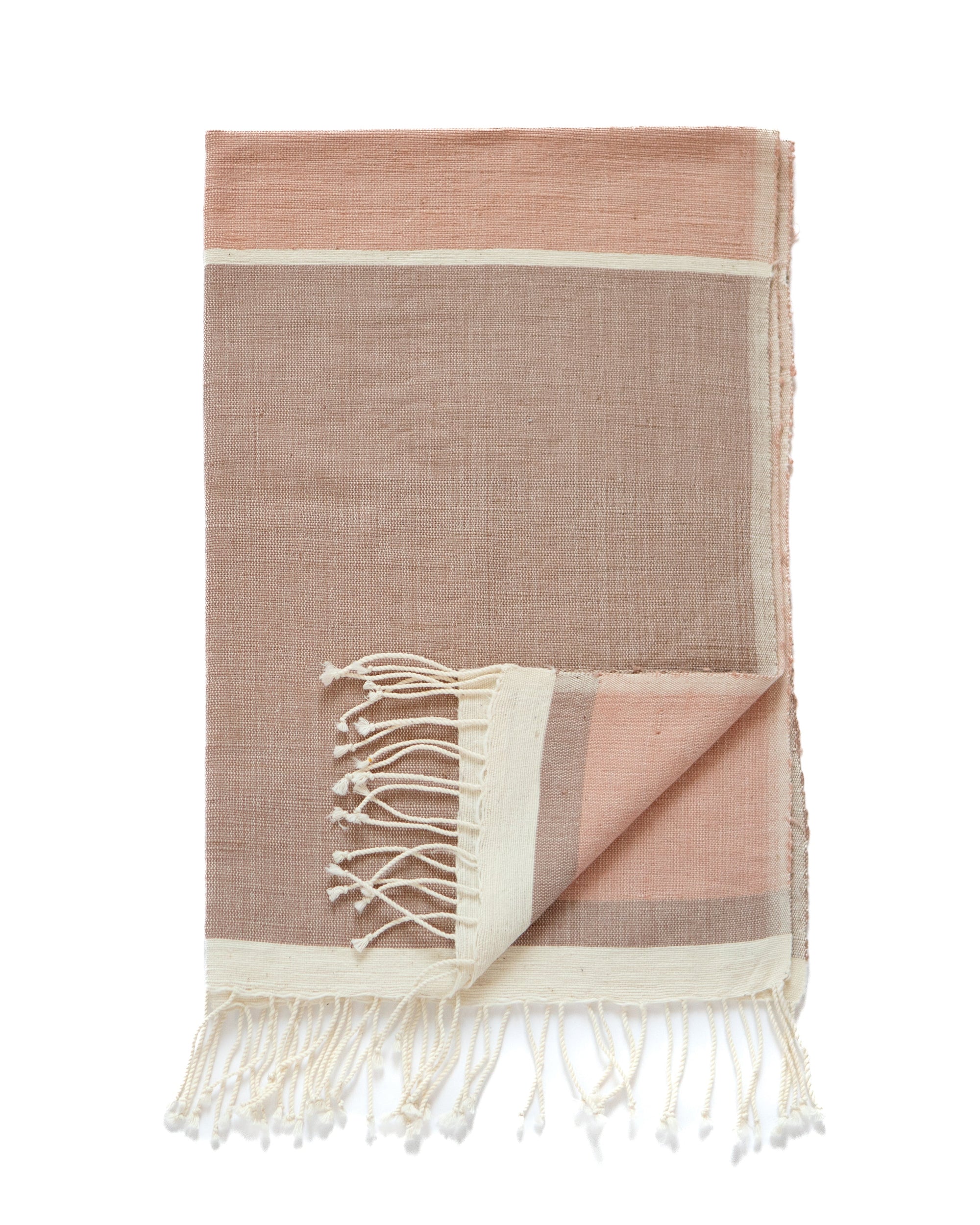 A blush coloured handwoven throw with fringes, featuring a color-blocked design in dusty pink and cream, shown on a plain white background.