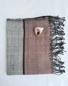 A hand woven small towel with dark fringes, laid flat on a white background. The left side is gray, the center-right is dusty mauve pink, and there is a thin dark vertical stripe between them.