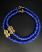 A blue beaded necklace with gold-colored accents on a dark background.