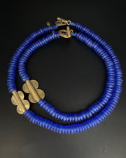 A blue beaded necklace with gold-colored accents on a dark background.