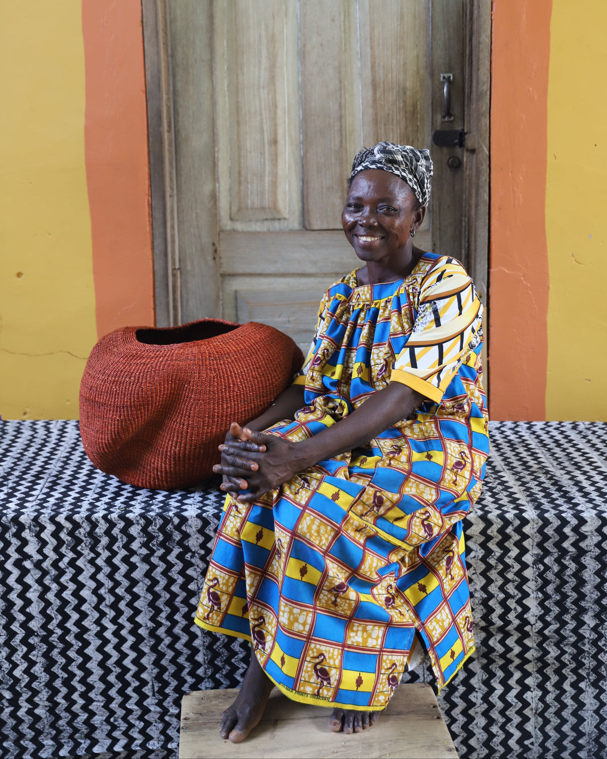 A person sitting on a bench with a traditional African basket in front of them.