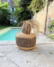 Tisanie Tia art basket with black and natural pattern and loose fringe beside a swimming pool