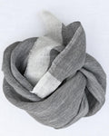 A light gray and white striped scarf, styled in a loose knot on a plain white background.