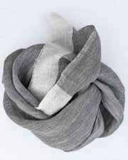 A light gray and white striped scarf, styled in a loose knot on a plain white background.