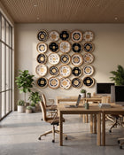 A modern office interior with light wood desks, beige chairs, potted plants, and a large wall-mounted circular decor piece made of many concentric rings in black, white, and natural wood tones.