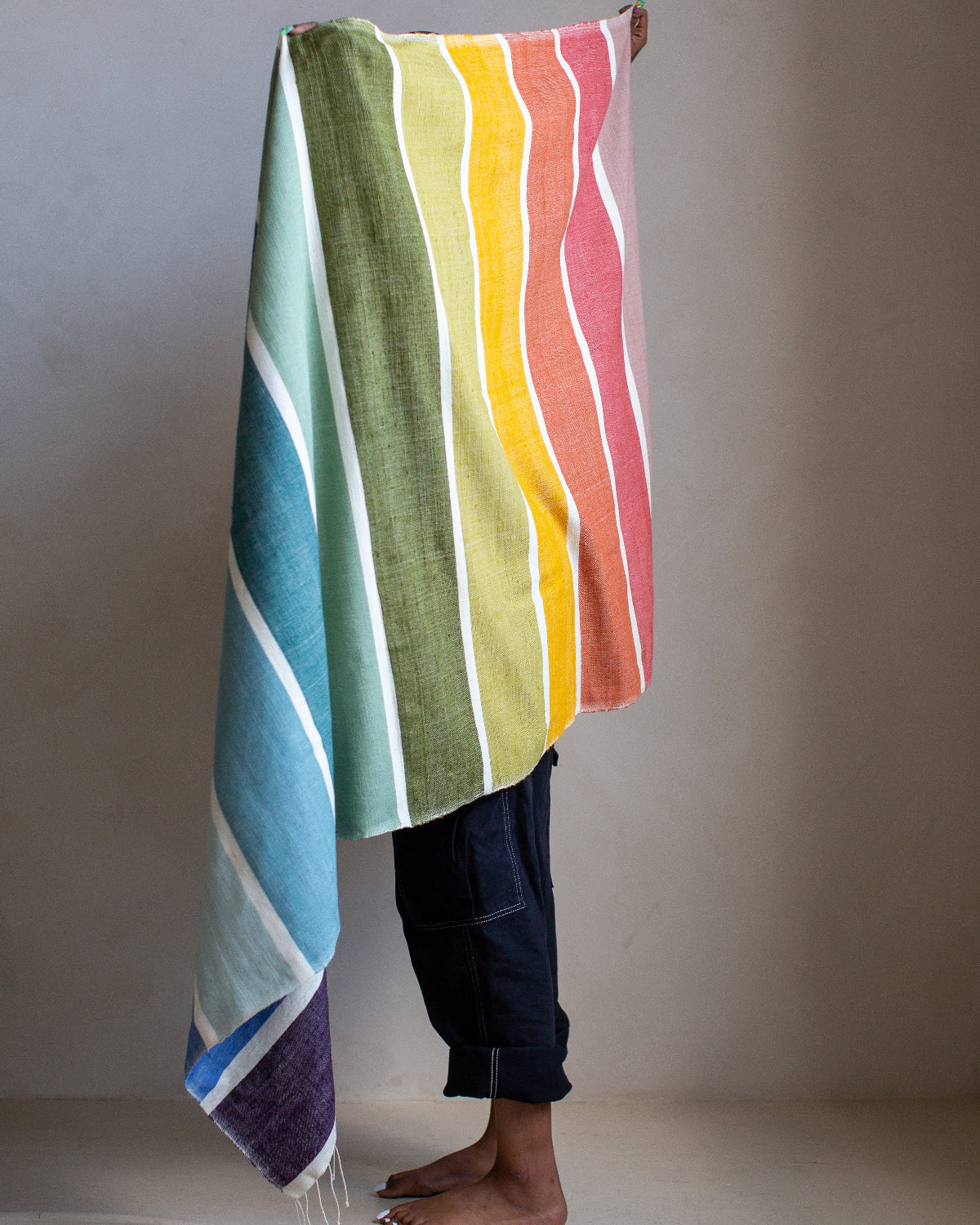 Colorful striped towel draped over a person against a plain background