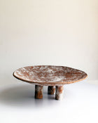 A terracotta coloured paper pulp Swazi platter with a white texture, featuring a round shape with three legs.