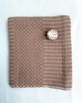 A blush colored cotton hand towel, laid flat on a white fabric background.