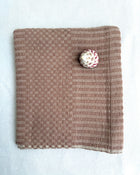 A blush colored cotton hand towel, laid flat on a white fabric background.