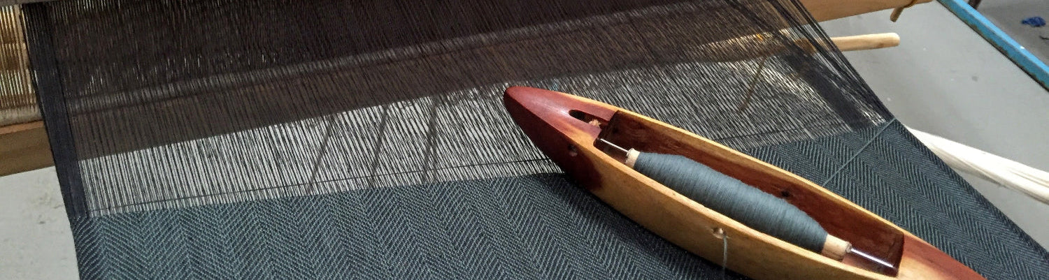 Weaving loom with a shuttle on a textured fabric background