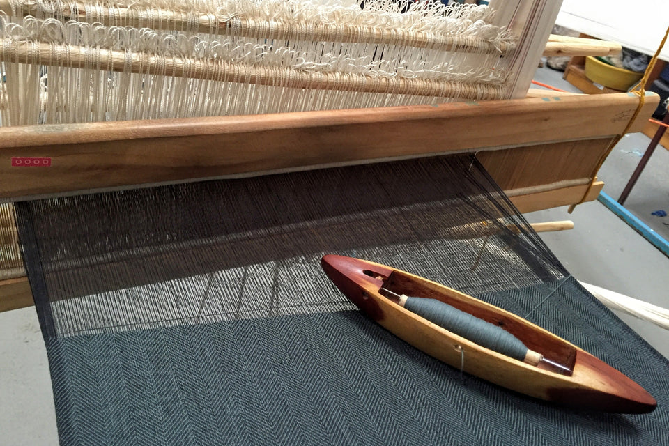 Weaving loom with a shuttle on a textured fabric background